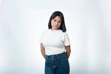 Stüdyoda poz veren kendine güvenen Endonezyalı bir kadının portresi. Temiz beyaz arkaplan ve sıradan kot giysili basit yaşam tarzı konsepti.