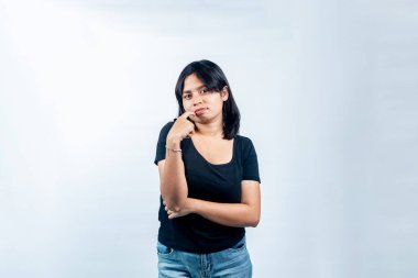 Asyalı genç bir kadının portresi. Elleri yüzlerinde kararsız ve tereddütlü görünüyor. Stüdyo ortamında şüphe, belirsizlik ve karar verme kavramı.