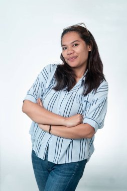 Kafasında gözlük olan neşeli bir Güneydoğu Asyalı kadın, beyaz bir arkaplanda kollarını kavuşturarak poz veriyor, güven ve profesyonel tutumu temsil ediyor..