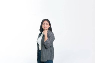 Kareli gömlekli genç bir Güneydoğu Asyalı kadın beyaz bir arka plana karşı durarak sakin ve düşünceli bir ifadeyle kameraya bakıyor..