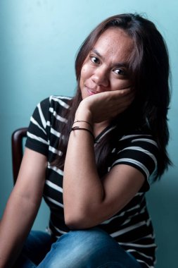 Elleri çenesinde poz veren Endonezyalı bir kadının portresi. Yaşam tarzı, sağlık ve mutluluk kavramları için otantik kapalı çekim.