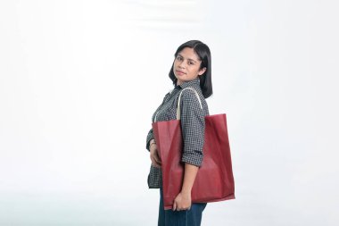 Büyük kırmızı bir çevre dostu çanta taşıyan Endonezyalı genç bir kadının portresi. Stüdyoda sürdürülebilir alışveriş ve plastiksiz yaşam tarzı kavramı.