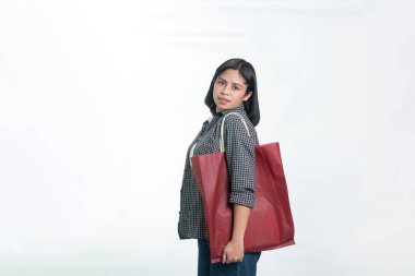 Büyük kırmızı bir çevre dostu çanta taşıyan Endonezyalı genç bir kadının portresi. Stüdyoda sürdürülebilir alışveriş ve plastiksiz yaşam tarzı kavramı.