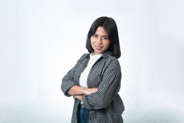 Kollarını kavuşturmuş, sıradan bir tişört giymiş gülümseyen Endonezyalı bir kadının portresi. Yaşam tarzı ve profesyonel kullanım için temiz stüdyo çekimi.