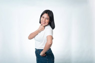 Beyaz arka planda genç bir Endonezyalı kadının portresi. Çenesinde bir el, belinde de beyaz bir gömlek ile gülümsüyor..