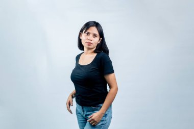 Beyaz bir arka planda duran genç Endonezyalı bir kadının portresi. Nazik bir gülümsemeyle, siyah bir gömlek giyerek ayakta duruyor ve ona bakıyordu..