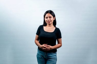 Beyaz bir arkaplan karşısında genç bir Endonezyalı kadının portresi, dostça bir ifadeyle kameraya bakıyor..