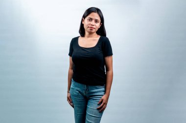 Beyaz bir arkaplan karşısında genç bir Endonezyalı kadının portresi, dostça bir ifadeyle kameraya bakıyor..