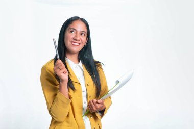 Sarı ceketli mutlu bir Endonezyalı kadın elinde bir kalem ve pano tutarken parlak bir ifadeyle yukarı bakıyor, yeni bir iş fikrini simgeliyor..