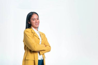 Sarı ceketli gülümseyen Endonezyalı bir kadının portresi kollarını kavuşturup beyaz bir stüdyonun arka planında kameraya bakıyor..