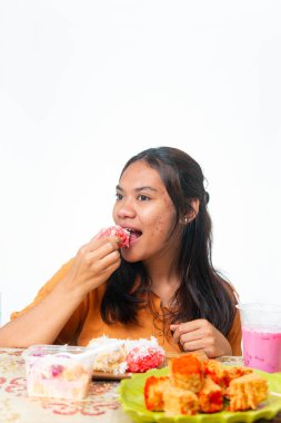 Endonezyalı kadın geleneksel atıştırmalıkların ve pembe içeceğin tadını çıkarıyor. Gıda ve yaşam tarzı içeriği için kopyalama alanı olan beyaz arkaplanda izole edilmiş.