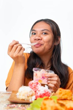 Endonezyalı kadın geleneksel atıştırmalıkların ve pembe içeceğin tadını çıkarıyor. Gıda ve yaşam tarzı içeriği için kopyalama alanı olan beyaz arkaplanda izole edilmiş.