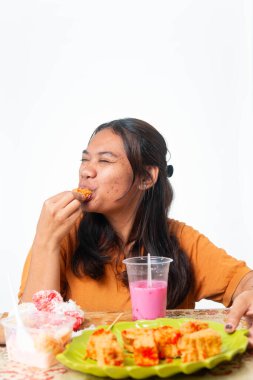 Endonezyalı kadın geleneksel atıştırmalıkların ve pembe içeceğin tadını çıkarıyor. Gıda ve yaşam tarzı içeriği için kopyalama alanı olan beyaz arkaplanda izole edilmiş.