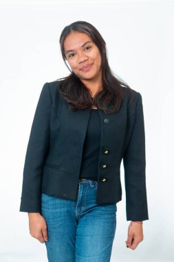 Siyah ceket ve kot pantolon giyen, siyah omuz çantası taşıyan, beyaz arka planda poz veren gülümseyen Endonezyalı kadın portresi..