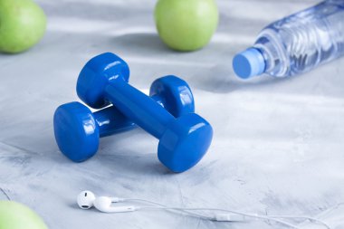 Halter, kulaklık, elma, şişe suyu gri arka plan üzerinde