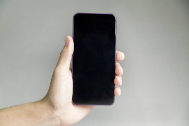 Tarafsız bir arkaplanda akıllı telefonu tutmak. Akıllı telefon konsepti. uygulama kavramı.
