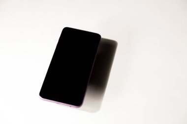 Gri bir masanın üstünde siyah ekranlı akıllı telefon. Cep telefonu konsepti. Gri konsept.