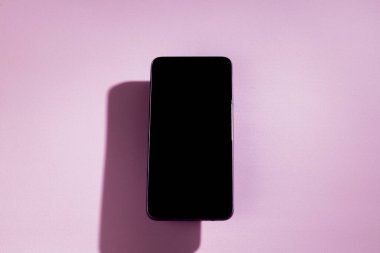Pembe bir masanın üstünde siyah ekranlı akıllı telefon. Cep telefonu konsepti. Gül konsepti.