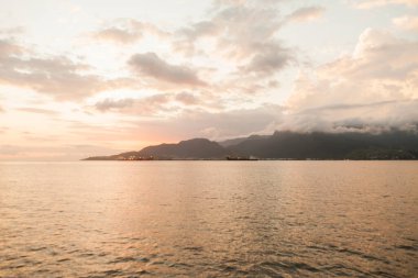 Golden sunset between rocks at Ilhabela beach. Paradisiacal and tropical Brazilian beach. Rocks concept. Golden sunset concept.
