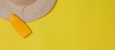 Sarı arka planda hasır şapka ve güneş kremi ambalajı. Mesaj için yer var. Şapka konsepti. Sombrero kavramı.