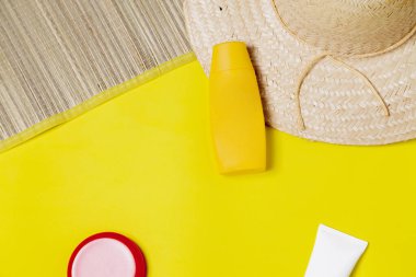 Plaj aksesuarları. Mat ve şapka, güneş kremi şişeleri ve renkli arka planda akıllı telefon. Plaj aksesuarları konsepti. Tatil konsepti. Metin için boşluk.