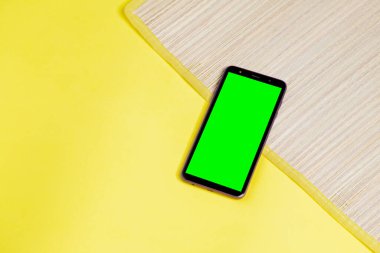 Sarı arka plandaki paspasın üzerinde yeşil ekran olan akıllı telefon. Akıllı telefon konsepti. yaz konsepti.