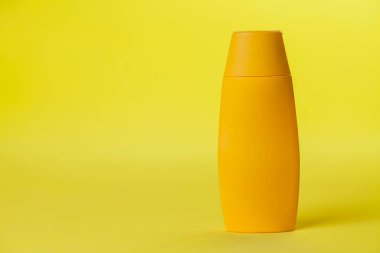 Renkli arka planda sarı güneş kremi şişesi. Güneş kremi. Deri bakımı konsepti. Mesaj için yer var. Model.