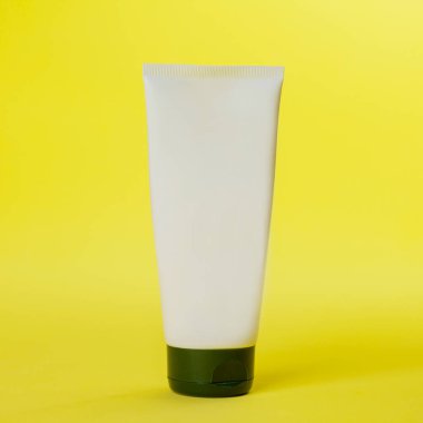 Sarı arka planda beyaz güneş kremi şişesi. Modelleme. Güneş kremi. Güzellik ürünü konsepti. Mesaj için yer var. Model.