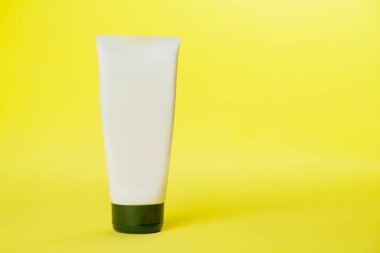 Sarı arka planda beyaz güneş kremi şişesi. Modelleme. Güneş kremi. Güzellik ürünü konsepti. Mesaj için yer var. Model.