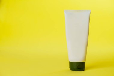 Sarı arka planda beyaz güneş kremi şişesi. Modelleme. Güneş kremi. Güzellik ürünü konsepti. Mesaj için yer var. Model.