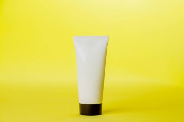 Sarı arka planda beyaz güneş kremi şişesi. Modelleme. Güneş kremi. Güzellik ürünü konsepti. Mesaj için yer var. Model.