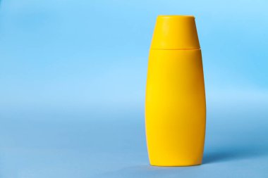 Mavi arka planda sarı tencere güneş kremi. Güneş kremi. Deri bakımı konsepti. Boşluğu kopyala.