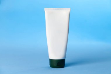 Mavi arka planda beyaz güneş kremi şişesi. Güneş kremi. Deri bakımı konsepti. Boşluğu kopyala.