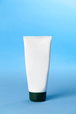 Mavi arka planda beyaz güneş kremi şişesi. Güneş kremi. Deri bakımı konsepti. Boşluğu kopyala.