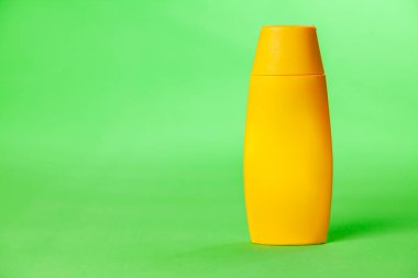 Yeşil arka planda sarı güneş kremi kavanozu. Model modeli. Yaz kavramı. Güneş koruma kavramı. Boşluğu kopyala.