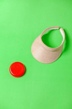 Yeşil arka planda bir kavanoz yüz kremi ve güneşlik. Deri bakımı konsepti. Ürün konsepti. Metin için boşluk.