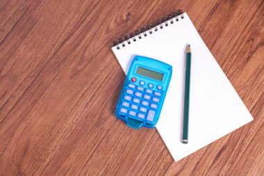 Hesap makinesinin POV 'u ve tahta bir masanın üzerinde boş bir not defteri. Finans konsepti. Ekonomi kavramı.