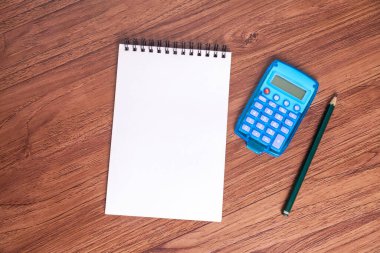 Hesap makinesinin POV 'u ve tahta bir masanın üzerinde boş bir not defteri. Finans konsepti. Ekonomi kavramı.