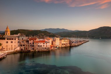 Turkuaz suları boyunca uzanan sakin bir Akdeniz liman kasabası, pastel evler, Korsika, Fransa