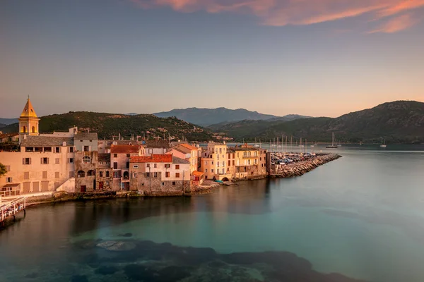 Turkuaz suları boyunca uzanan sakin bir Akdeniz liman kasabası, pastel evler, Korsika, Fransa