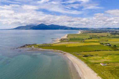 Sakin bir sahil şeridi, kumlu bir sahil ve uzak dağlara doğru uzanan yeşil alanlar. Kırsal çiftlikler, çiftlik evleri ve çalılıklar seyahat ve doğa temaları için ideal barışçıl ve manzaralı bir manzara yaratıyor.