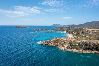 Kayalık bir kıyı manzarası, küçük bir ada kalesi, berrak turkuaz sular, Sardunya, İtalya