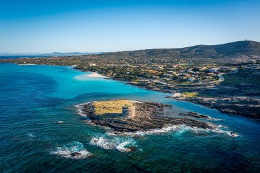 Berrak turkuvaz suları, kayalık kıyıları ve küçük bir ada kalesi olan Sardunya, İtalya 'nın güneşli kıyı kasabasını kuşların gözünden gören bir manzara.