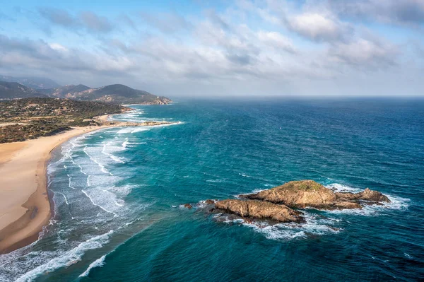 A expansive coastal view featuring golden sand, turquoise water, and rocky outcrops, Sardinia, Italy