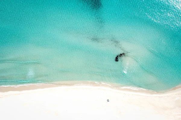 An expansive aerial shot of turquoise water meeting a pristine white-sand beach, Sardinia, Italy