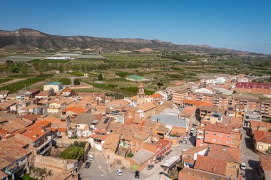 Aerial View Of A Rustic Village With Red Roofs, Green Fields, And Distant Hills, La Granja d'Escarp, Spain