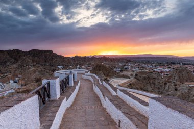 Titrek günbatımı, Guadix, Sierra Nevada, İspanya 'daki engebeli tepelerden süzülen beyaz duvarlı bir merdivenin üzerine sıcak turuncu ışık saçıyor.