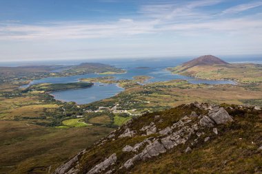 Adaların, körfezlerin ve yemyeşil tepelerin bulunduğu geniş bir kıyı bölgesi manzarası. Sakin mavi sular, küçük köyler, Connemara, İrlanda