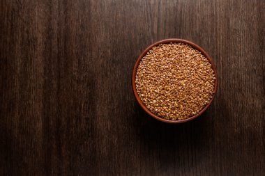 Yukarıdan koyu renkli ahşap izole çiğ çiğ buğday Rustik Seramik kase