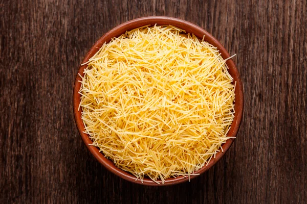 Pişmemiş makarna yukarıdan koyu renkli ahşap izole Rustik Seramik kase